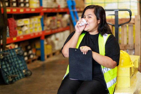 A warehouse worker inside a warehouse drinking tea.